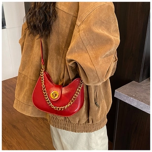 Détail du sac croissant rouge en cuir brillant avec chaîne dorée sur le mannequin