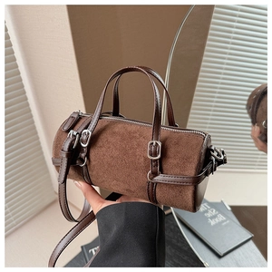 Detail view of brown suede cylinder boston bag with adjustable strap held by model