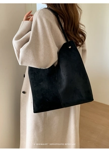 Minimalistische schwarze Wildleder-Einkaufstasche am Modell mit beigem Mantel getragen