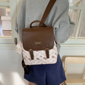Détail d'un sac à dos chic à carreaux crème et marron avec rabat en cuir et pompon en peluche