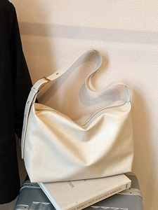 Large beige soft faux leather hobo bag with adjustable strap for women in a lifestyle setting