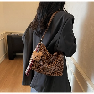 Close-up of leopard print hobo bag with brown leather strap and plush bear charm