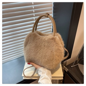 Detail view of the soft faux fur texture and leather handle on a khaki plush handbag