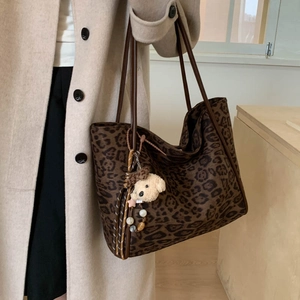 Detail of large leopard print tote bag with brown straps and plush bear charm