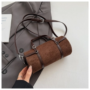 Macro shot of dark brown cylindrical crossbody bag featuring matte texture and silver hardware