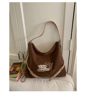Detail of leopard print hobo bag with embroidery and decorative metal buckle straps