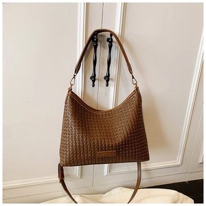 Detail shot of deep brown woven texture and adjustable shoulder strap on a Hobo style bag