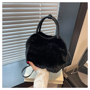 Detailed view of black faux fur handbag with circular leather handles and slim strap