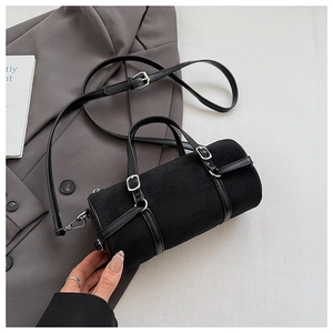 Close-up of black suede cylinder bag with leather straps and silver metal buckles
