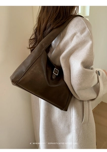 Detail of dark brown leather tote bag with retro metallic buckle and wide shoulder strap