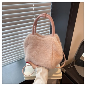 Detail of soft pink faux fur texture and leather handle on a stylish crossbody tote bag