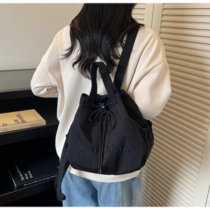 Close-up of black drawstring backpack with YOU BEAR embroidery and nylon texture