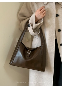 Close-up of dark brown vintage faux leather tote bag featuring a metallic buckle detail