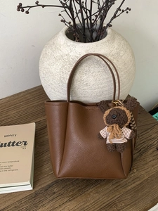 Brown litchi grain bucket tote bag with cute crochet bear charm on a rustic background