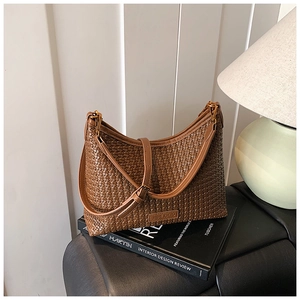 Detail of a brown woven hobo bag with adjustable strap and leather brand logo