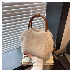 Detailed close-up of soft plush tote bag with brown leather handles and strap
