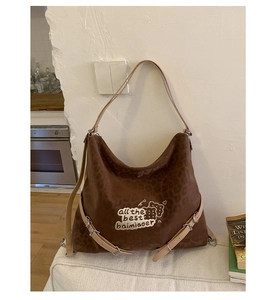 Close-up of leopard print shoulder bag with beige leather straps and embroidered patch