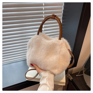 Detail of white fluffy handbag with brown leather handles and smooth circular hardware