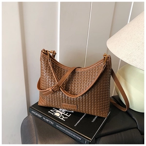 Detailed close-up of brown woven texture and brand logo on a retro shoulder bag