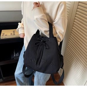 Detail of black drawstring backpack with You I Bear embroidery and side pockets