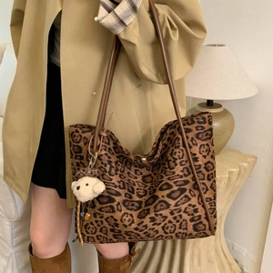 Detail of leopard print tote bag with brown straps and cute plush bear charm