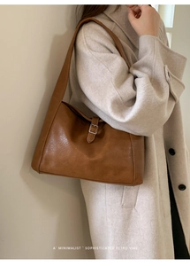 Detailed close-up of brown faux leather hobo bag with vintage metal buckle accent
