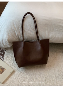 Detail of dark brown leather tote bag with lychee grain texture and long shoulder strap