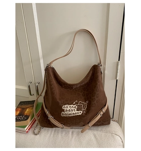Detail of leopard print hobo bag showing embroidery and adjustable leather strap with silver buckles