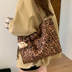Rear view of a model wearing the large leopard print tote bag with a plush bear charm