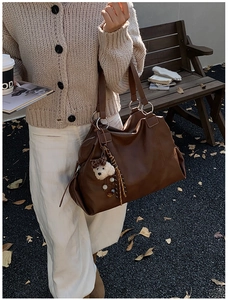 Dettaglio della grande borsa tote vintage marrone con ciondolo a orsetto in stile autunno