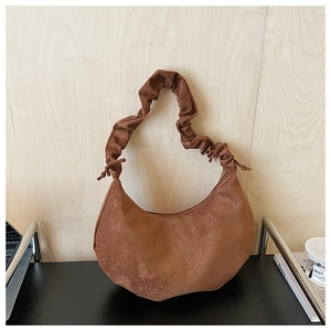 Detail of brown crescent bag featuring pleated cloud strap and faux suede texture