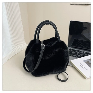 Detail of black faux fur handbag featuring leather-look handles and long shoulder strap