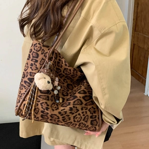 Detailed side view of leopard print tote bag with plush bear charm and brown straps