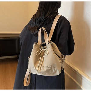 Detail of beige drawstring backpack with YOUJI BEAR embroidery and adjustable shoulder straps