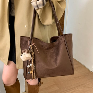 Detail view of large brown faux suede tote bag with fringe and dog charm pendant