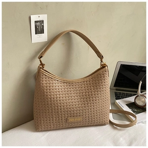Detail of beige woven texture shoulder bag featuring metallic logo and top handle
