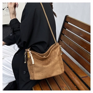 Détails de la bandoulière en cuir tressé et charms en perles colorées sur le sac hobo en daim