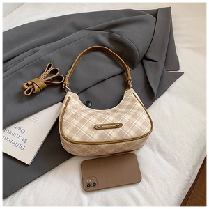 Detailed view of beige checkered crescent bag with leather trim on gray blazer