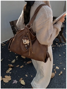 Dettaglio borsa tote grande marrone in ecopelle con cuciture e ciondolo orsetto di peluche