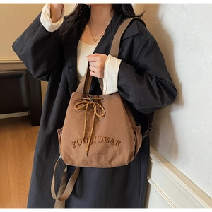 Detail view of coffee canvas bucket backpack with YOUJI BEAR embroidery and drawstring closure