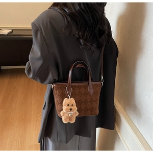 Detail of dark brown bucket bag with quilted suede texture and plush bear charm