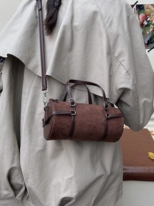 Retro brown suede barrel crossbody bag with leather trim worn by model in trench coat