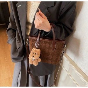 Détail du sac seau en daim marron foncé avec motifs embossés et breloque ourson