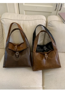Close-up of retro leather tote bags with silver buckle and vintage texture on soft sofa