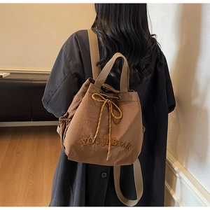 Deep brown bucket backpack with YOU JI BEAR embroidery shown in a lifestyle setting