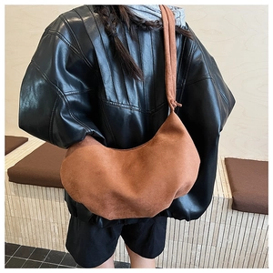 Detail of a brown suede hobo bag featuring drawstring pleats and a decorative knotted strap