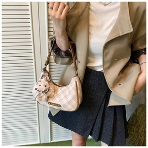 Detail of pink plaid hobo bag featuring brown leather handle and cute plush rabbit charm