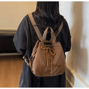 Detail of dark coffee drawstring backpack with YOU JI BEAR embroidery and adjustable straps