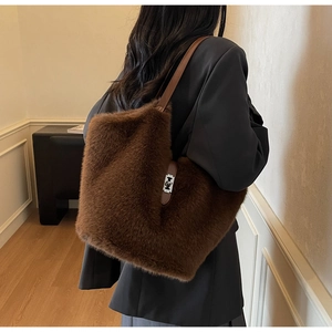 Detail of dark brown plush tote bag with silver metal turn-lock on a stylish model