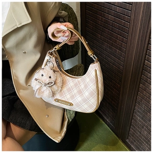 Close-up of woven checkered hobo bag with pink plush bunny charm and brown leather trim
